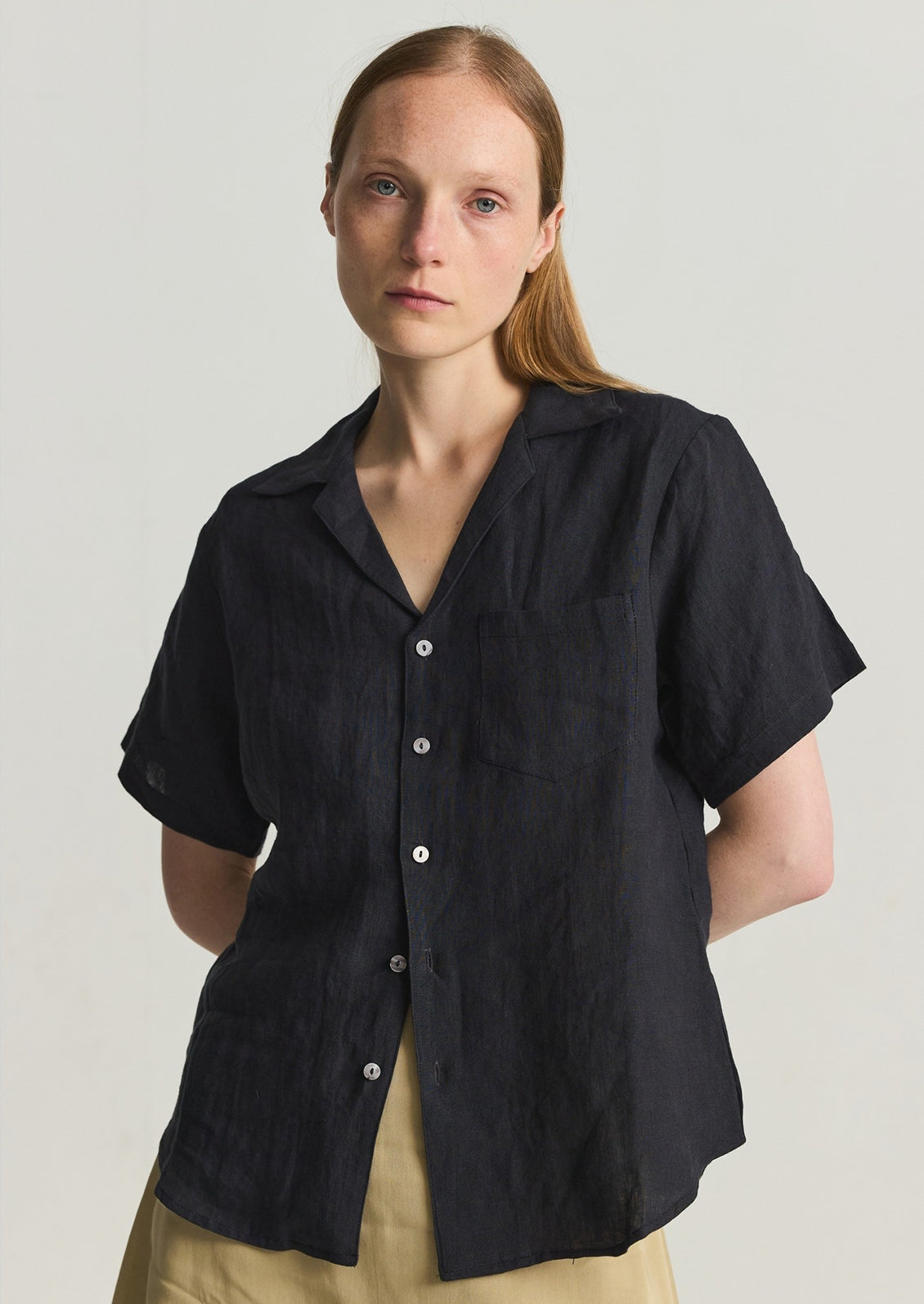 A woman in a black linen shortsleeved button-up. 