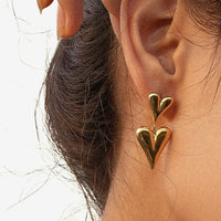 2: A pair of gold earrings with small heart on top of big heart.