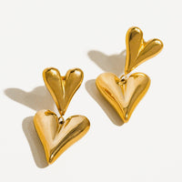 1: A pair of gold earrings with small heart on top of big heart.