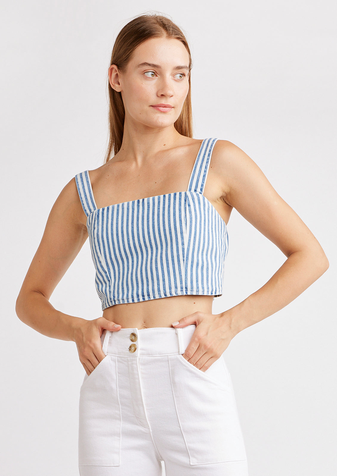 A woman wearing a square neck crop top with thick blue stripes.