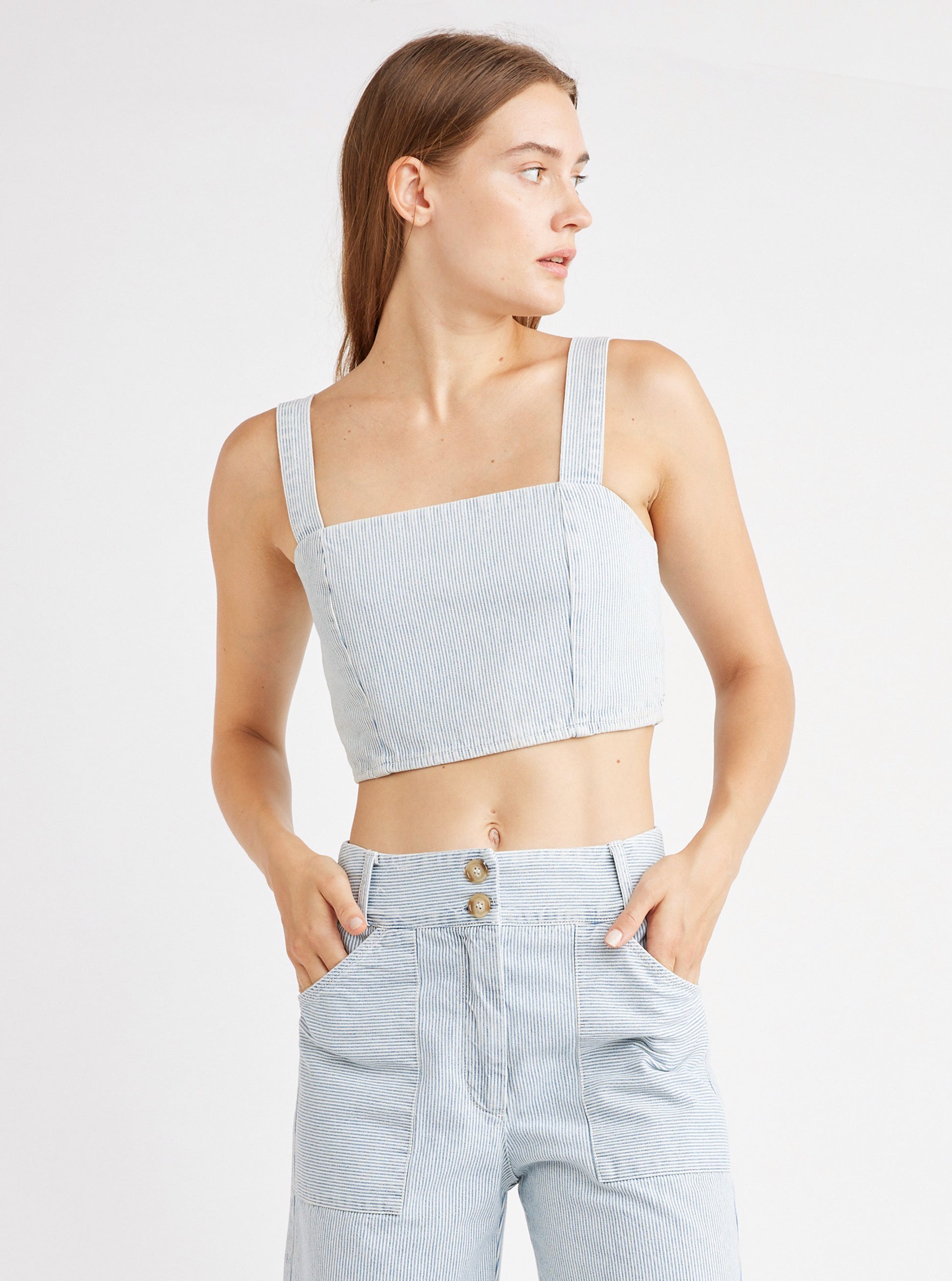 A woman wearing a square neck crop top with small blue and white pinstripe pattern.