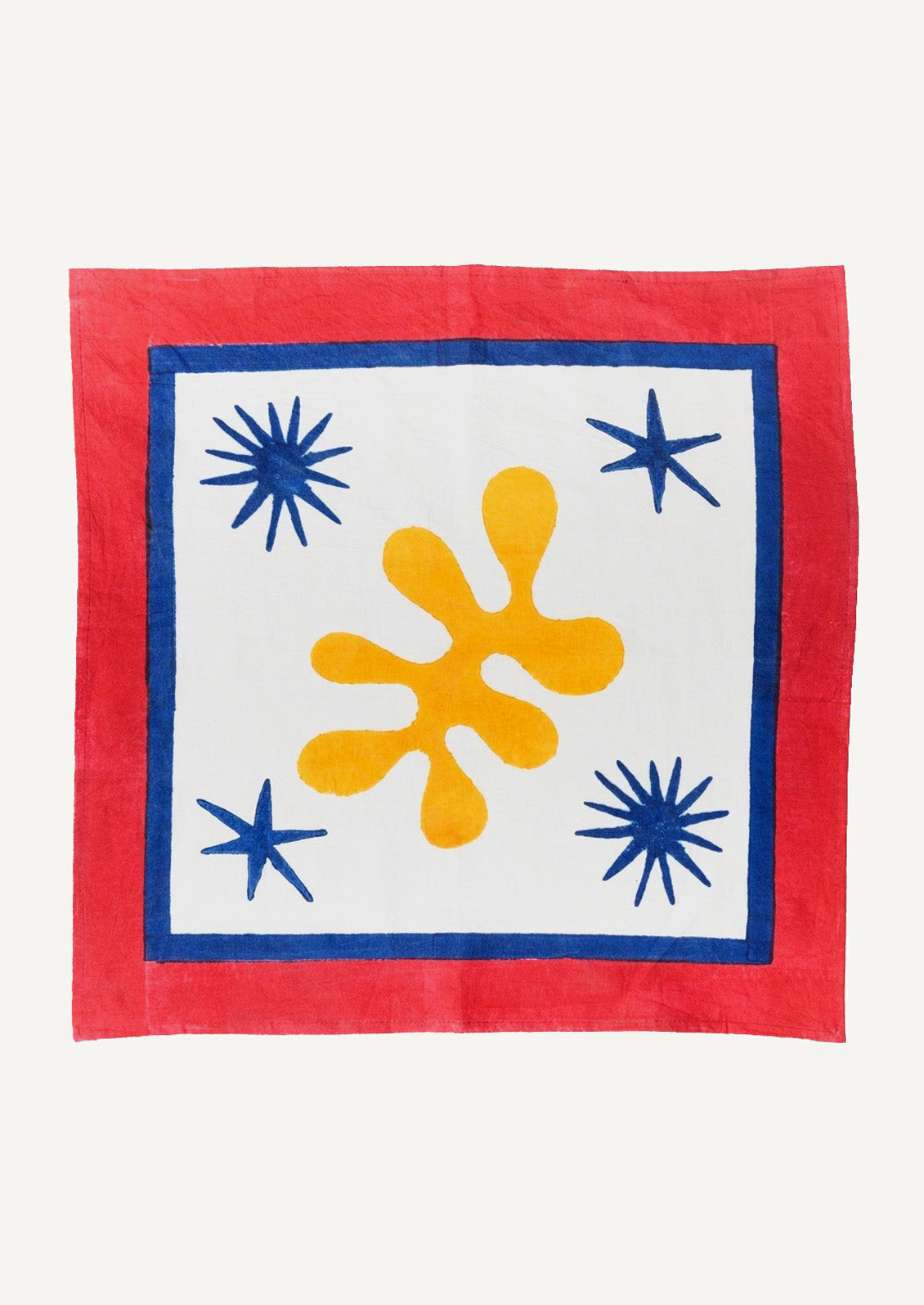 A block printed cotton napkin with Matisse-inspired star and leaf pattern in primary colors.