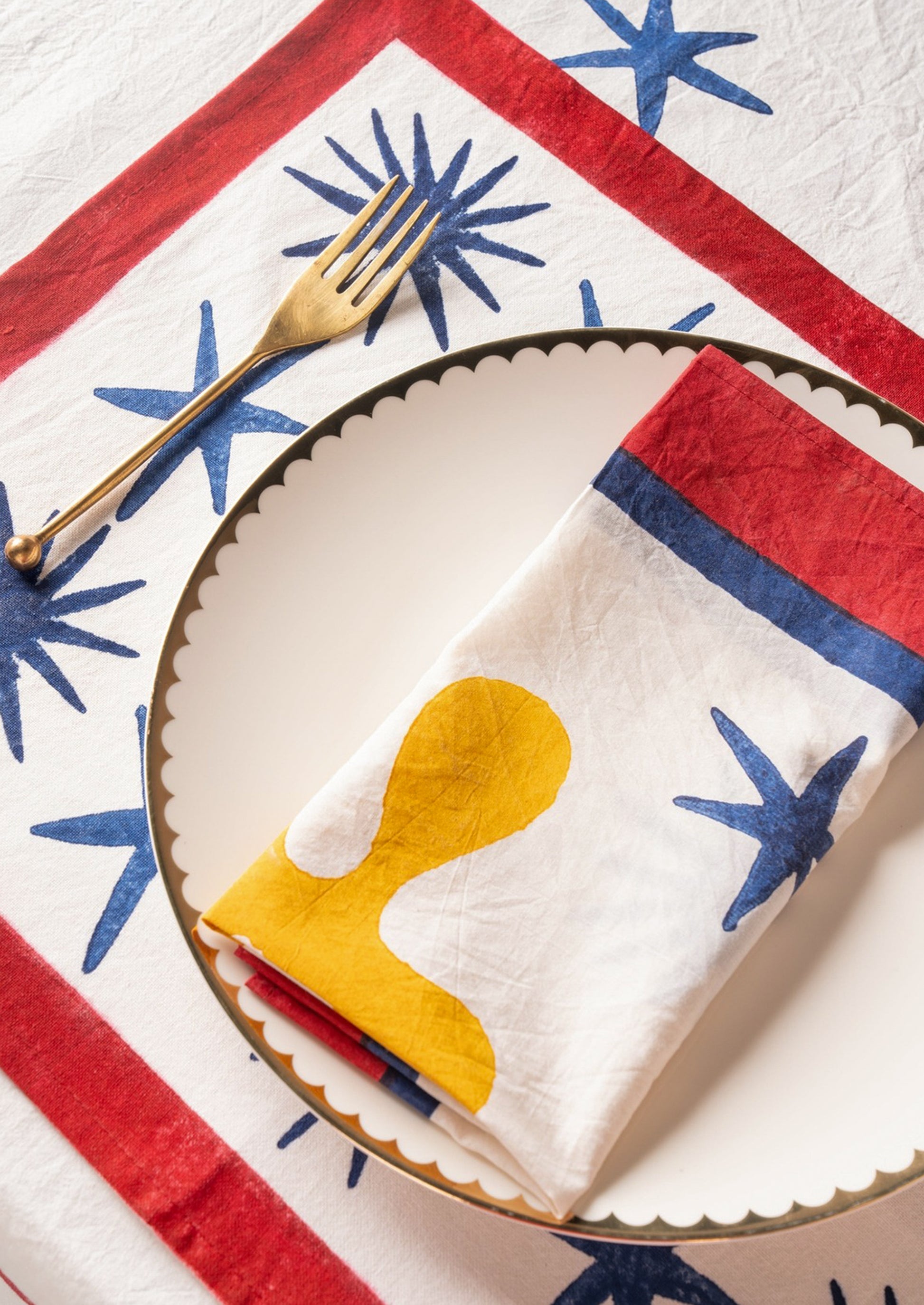 A block printed placemat in white with blue stars and red border.