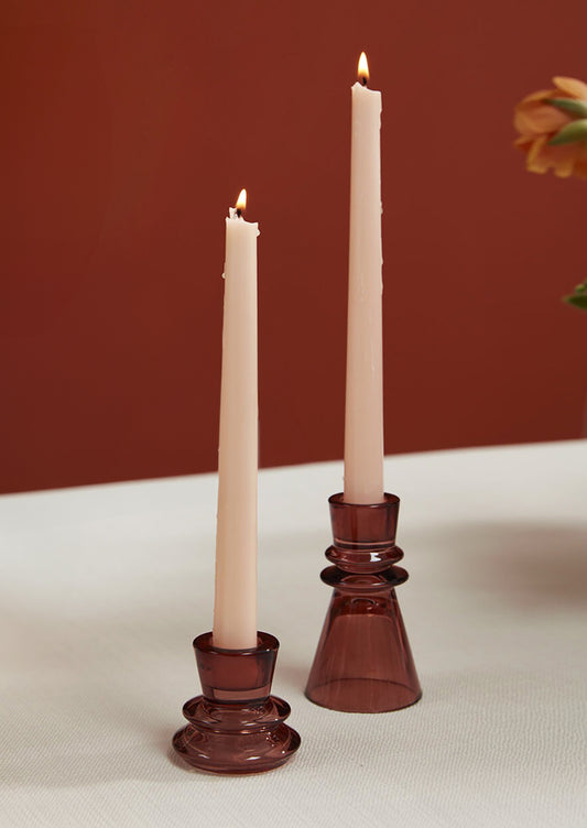 A pair of burgundy colored glass taper candle holders with tapered geometric shape.