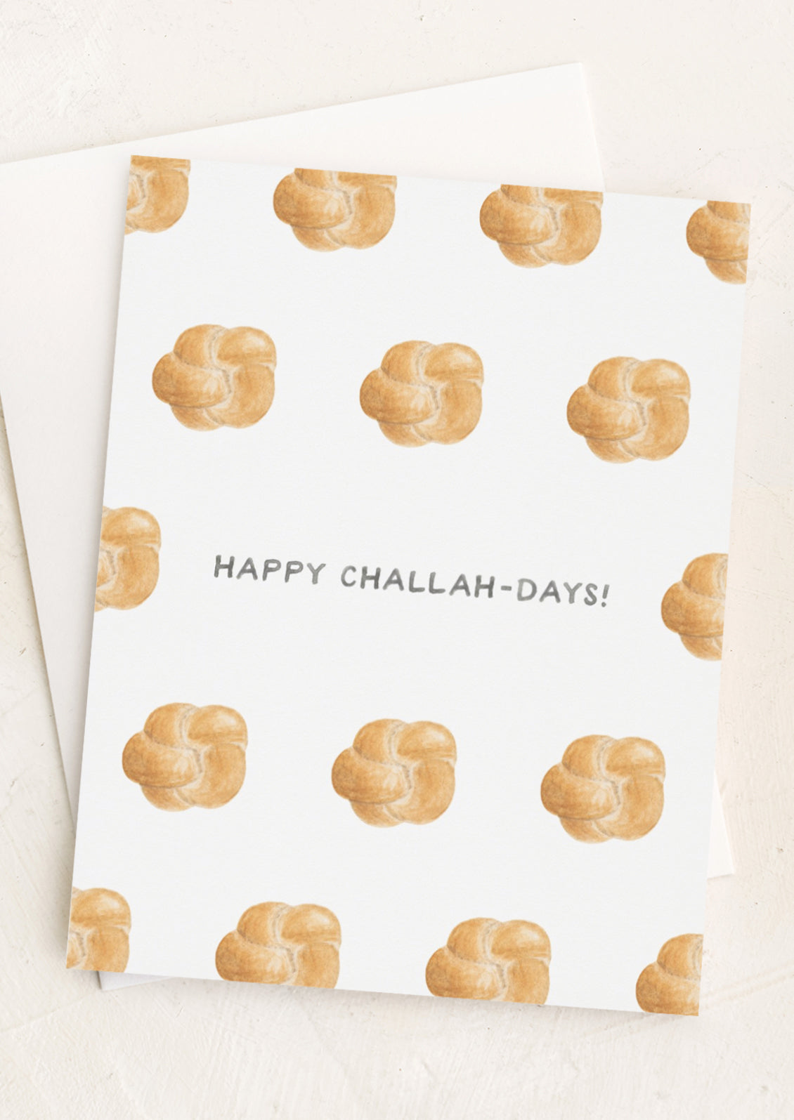 A greeting card with illustrations of challah bread and text at center reads "Happy Challah-Days!"