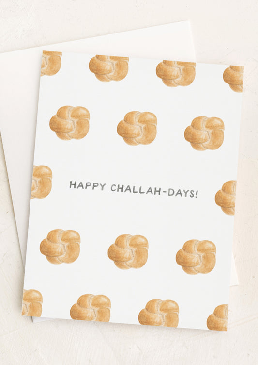 A greeting card with illustrations of challah bread and text at center reads "Happy Challah-Days!"