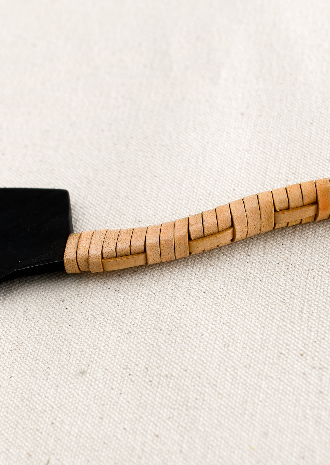 A black cast iron knife with natural leather wrapped handle.