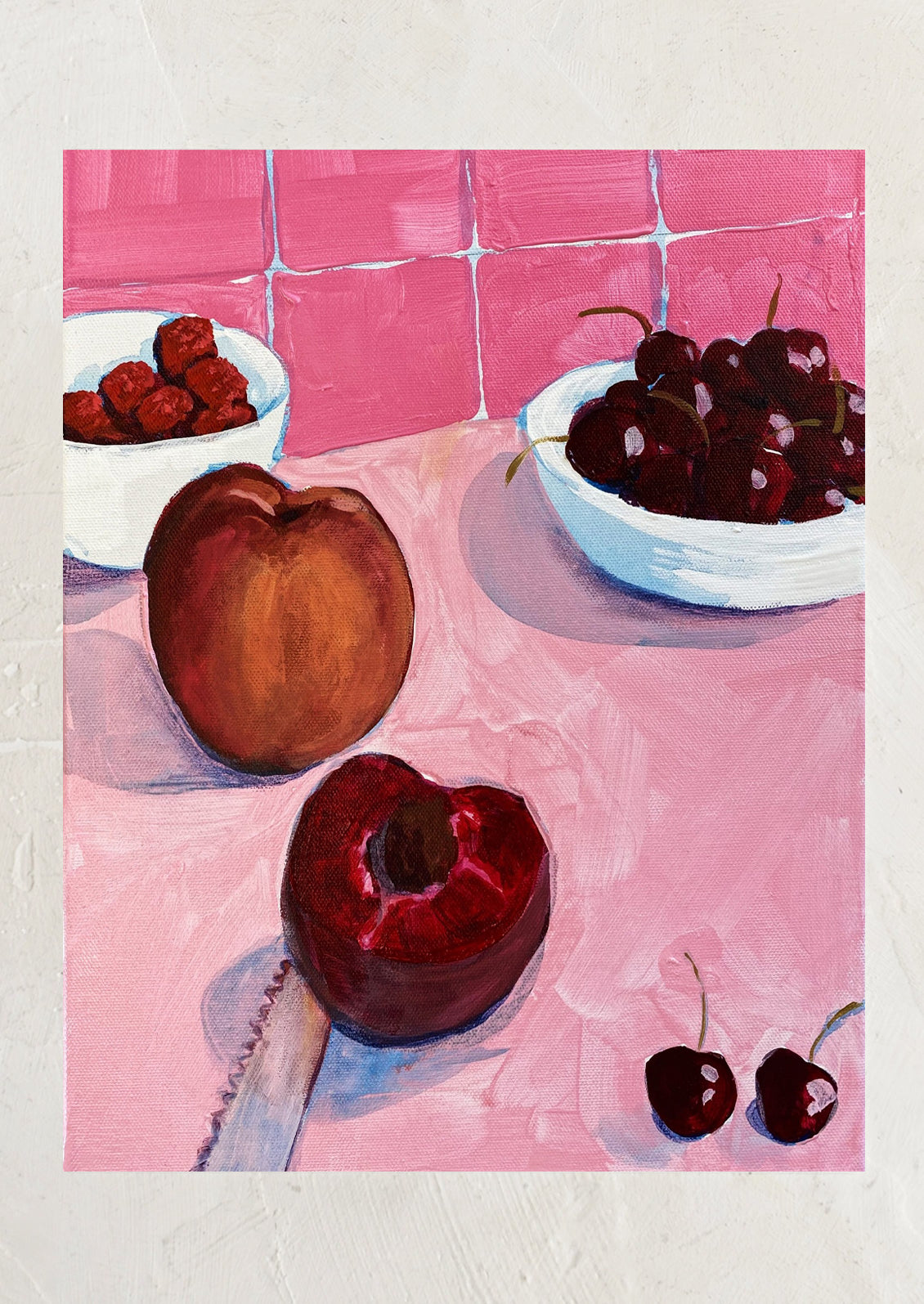 An art print of a painting depicting fruit sitting on a pink kitchen counter with pink tile backplash.