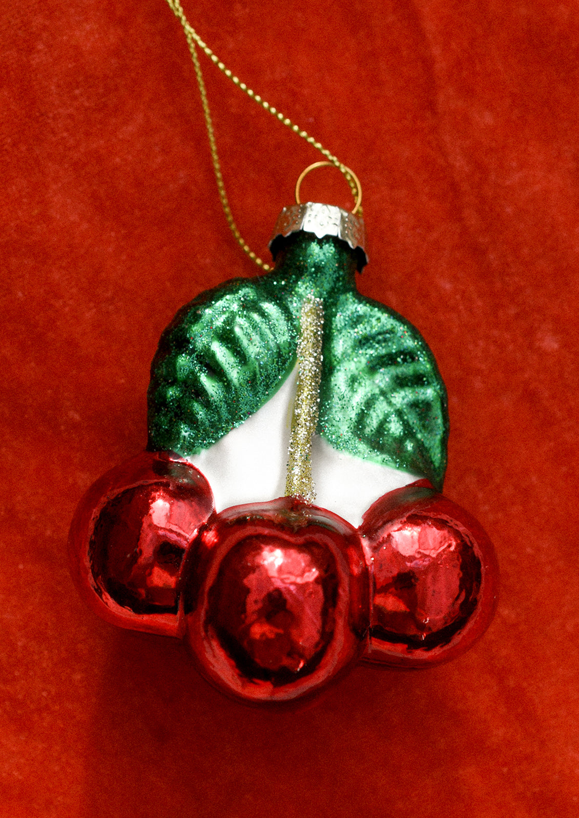 A glass ornament depicting a bunch of red cherries.