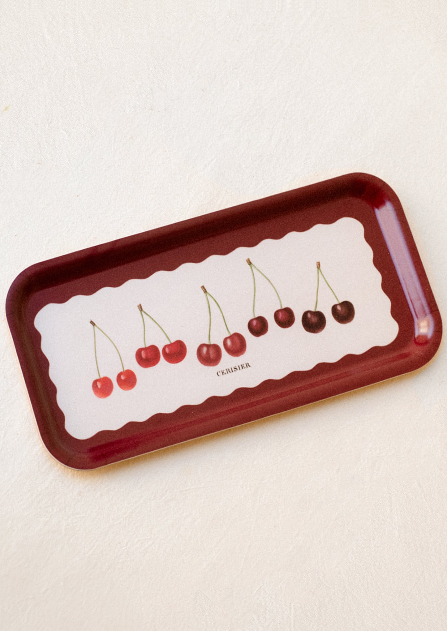 A rectangular laminated birchwood tray with wavy shape and cherry print, text reads "Cerisier".