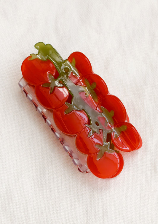 A clear hair claw with red cherry tomatoes on green vine.