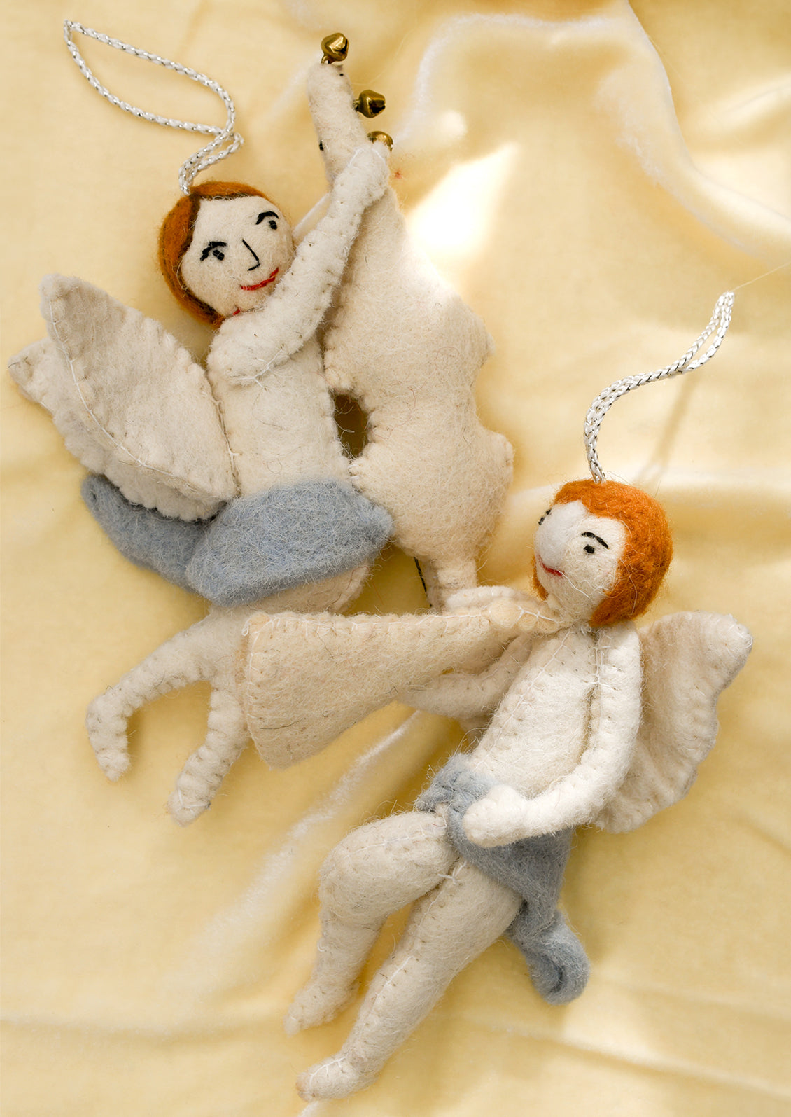 A felt ornament of a cherub wearing blue skirt, holding musical instrument.