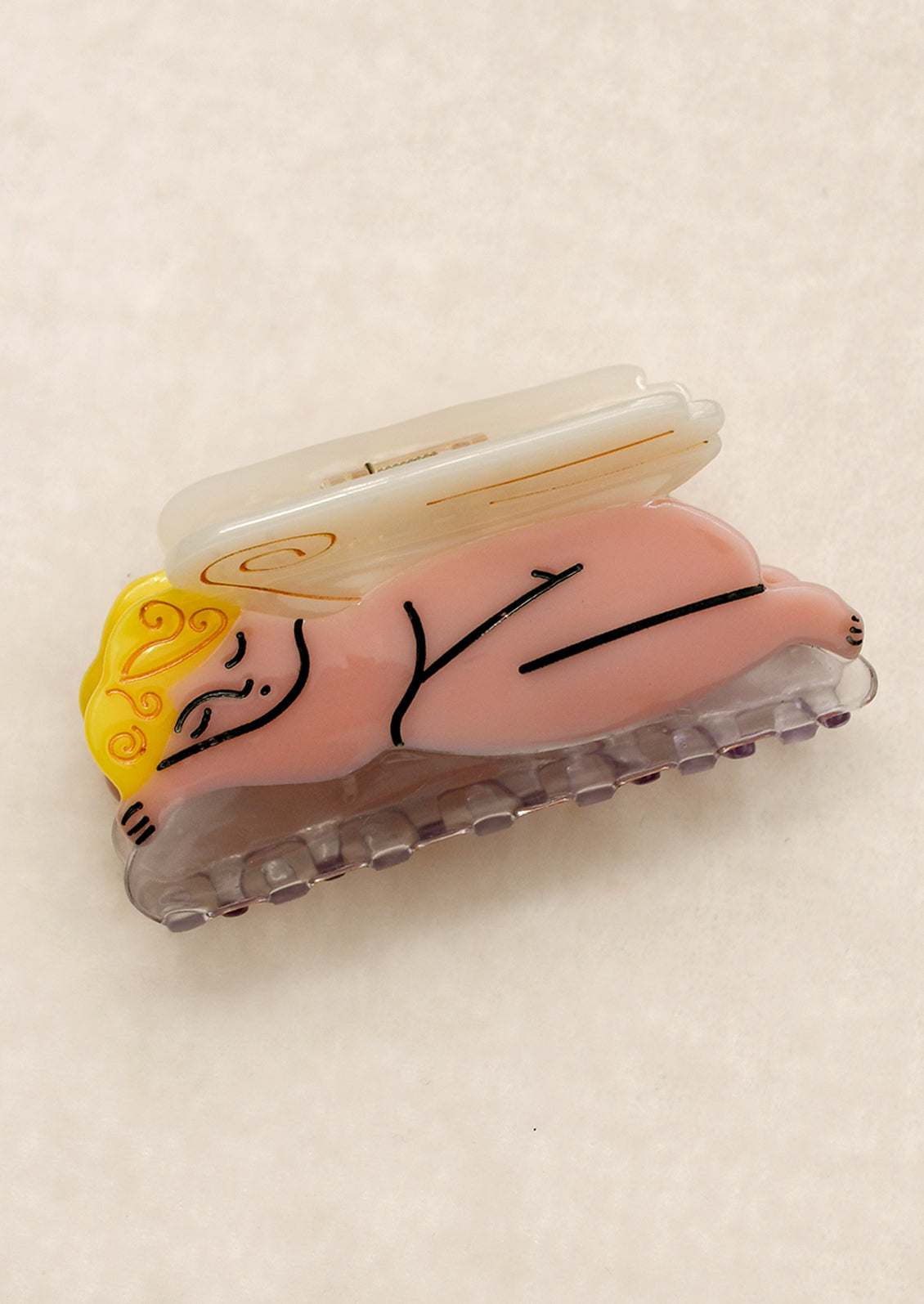 An acrylic hair claw depicting a nude sleeping cherub.