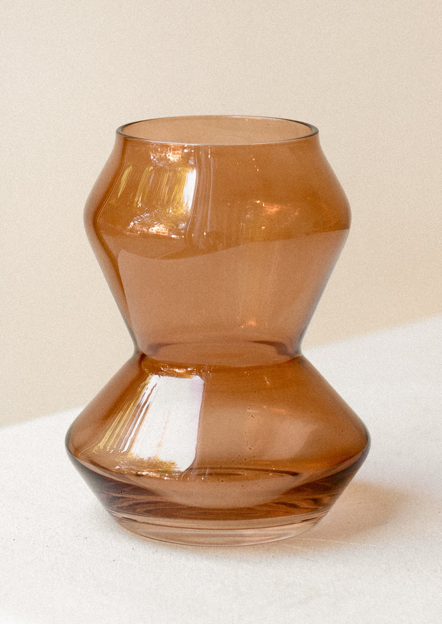 A glass vase in transparent amber hue with tapered conical shape.