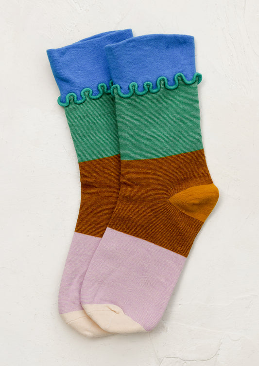 A pair of multicolor color blocked socks with squiggly ruffle trim at ankle.