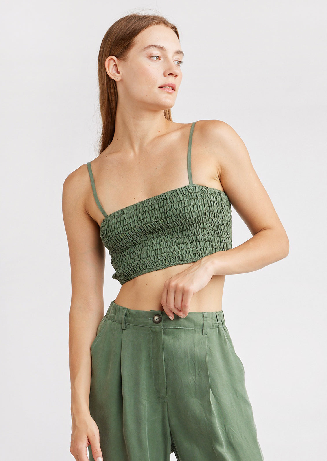 A woman wearing a smocked green spaghetti strap crop top.