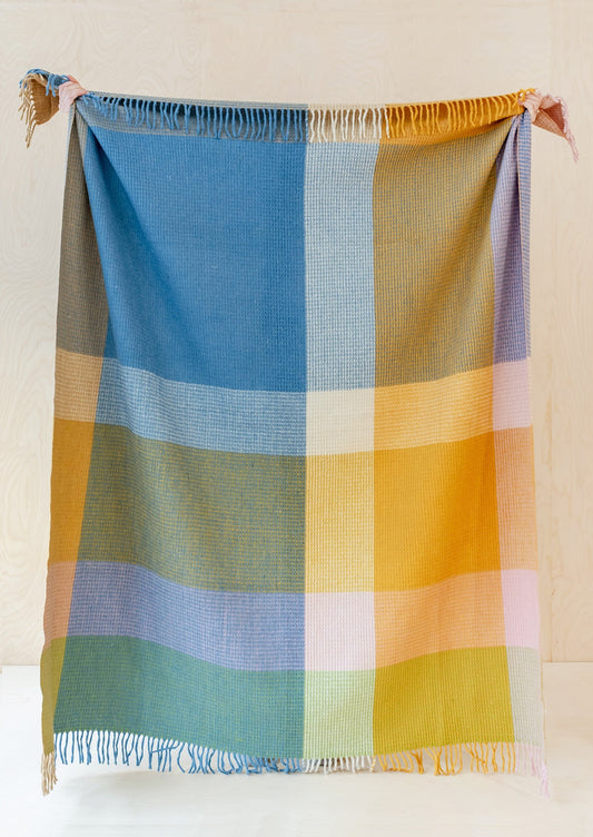 A colorblock large check patterned throw in cobalt, yellow, aqua and orange tones.