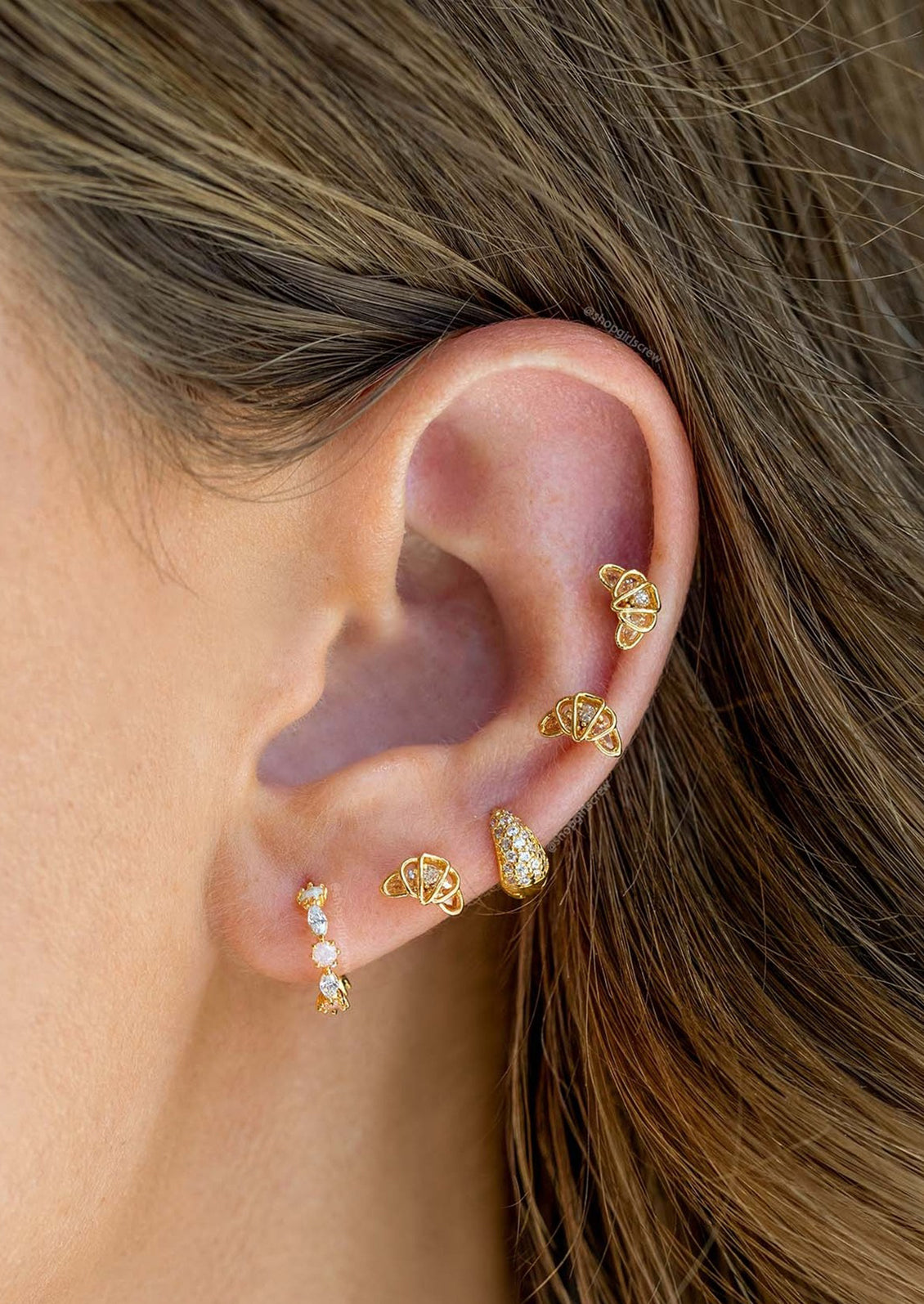 A pair of tiny stud earrings in the shape of croissant.