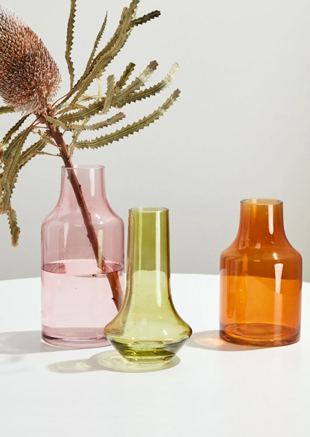 Amber: Three transparent glass vases in assorted colors and shapes.