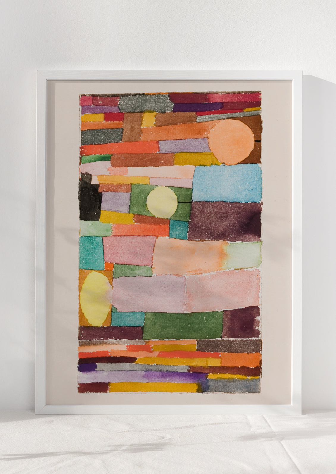 An art print of colorful abstract shapes stacked together, in white frame.