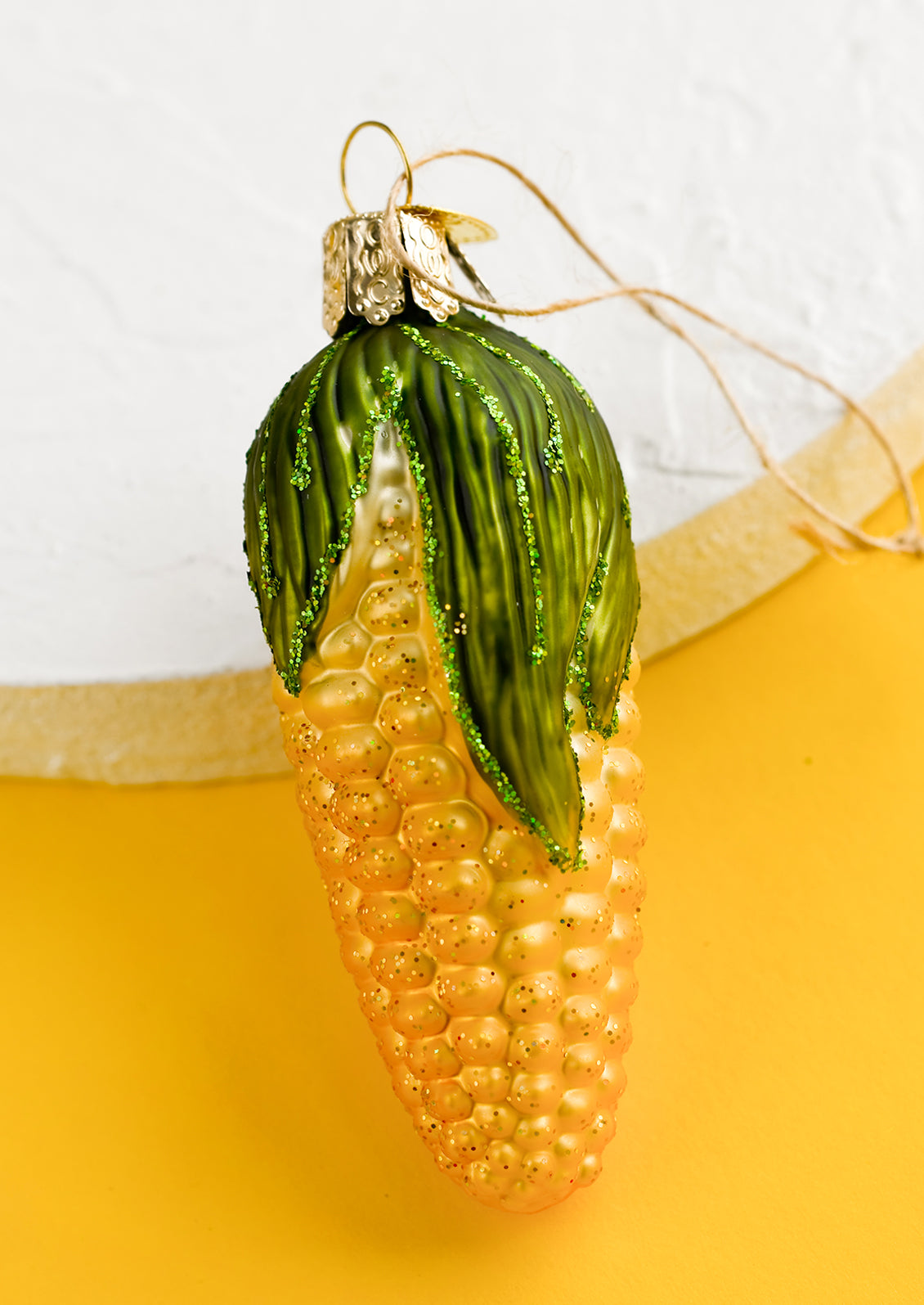 A glass ornament of ear of yellow corn.