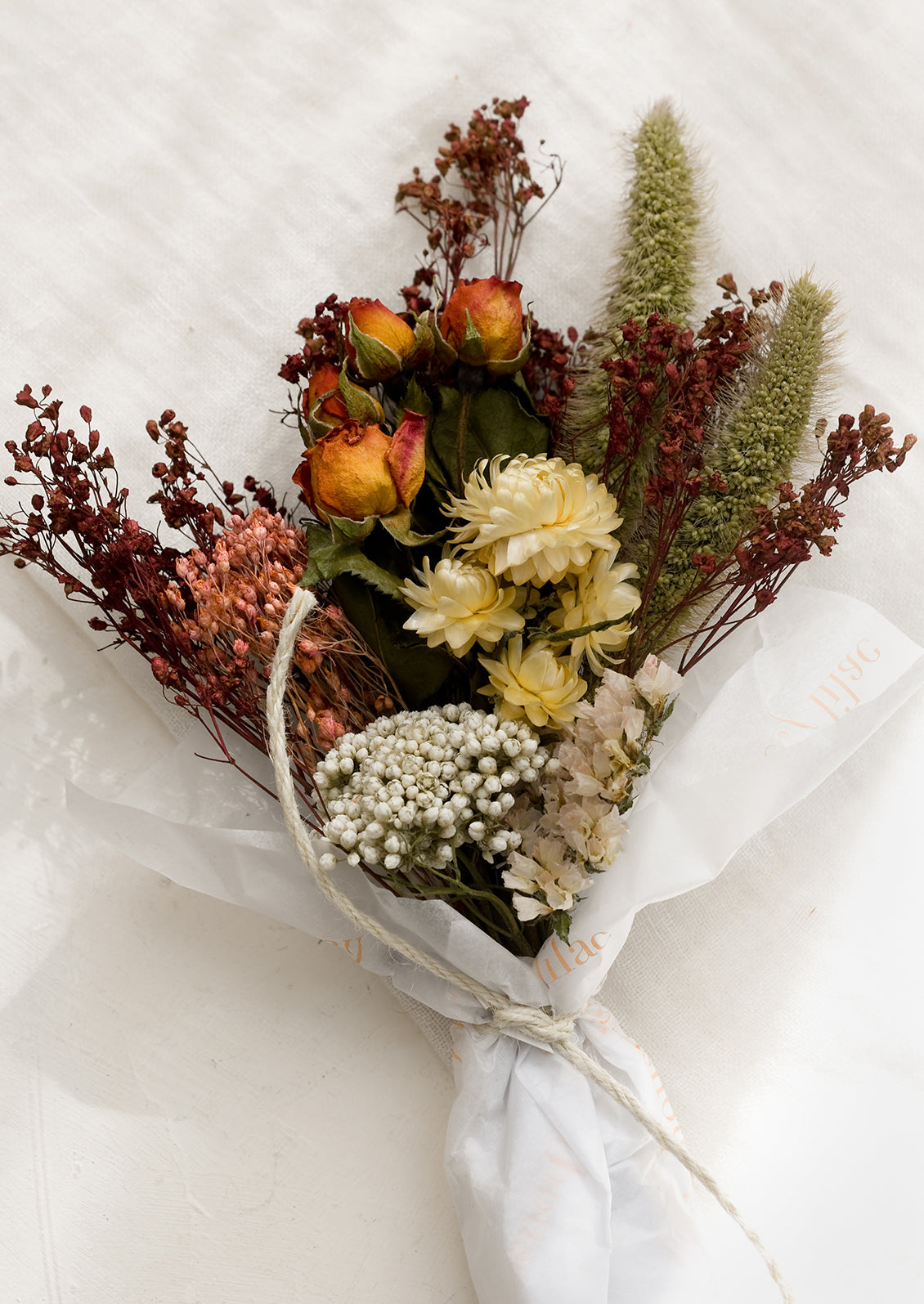 A bouquet of dried flowers in a ivory, green, white and pink mix.