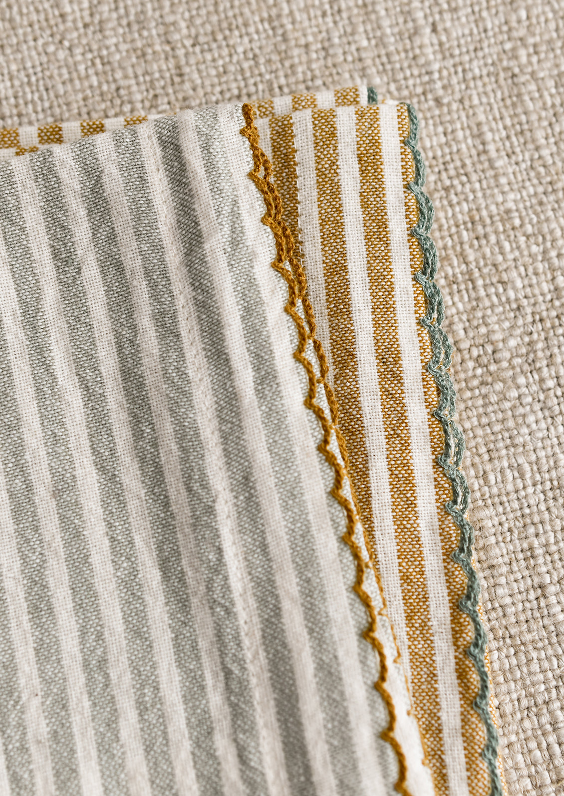 A set of four striped dinner napkins in grey-blue and brown stripes.