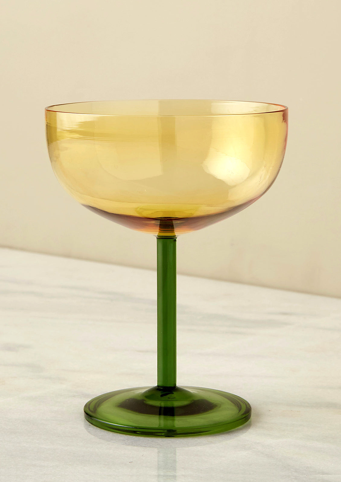 A two tone coupe glass with yellow upper and green stem.