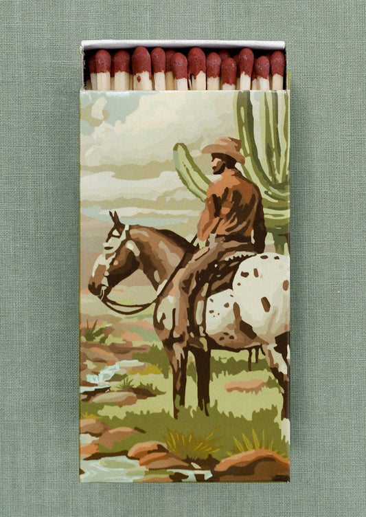 A printed matchbox with desert cowboy design.