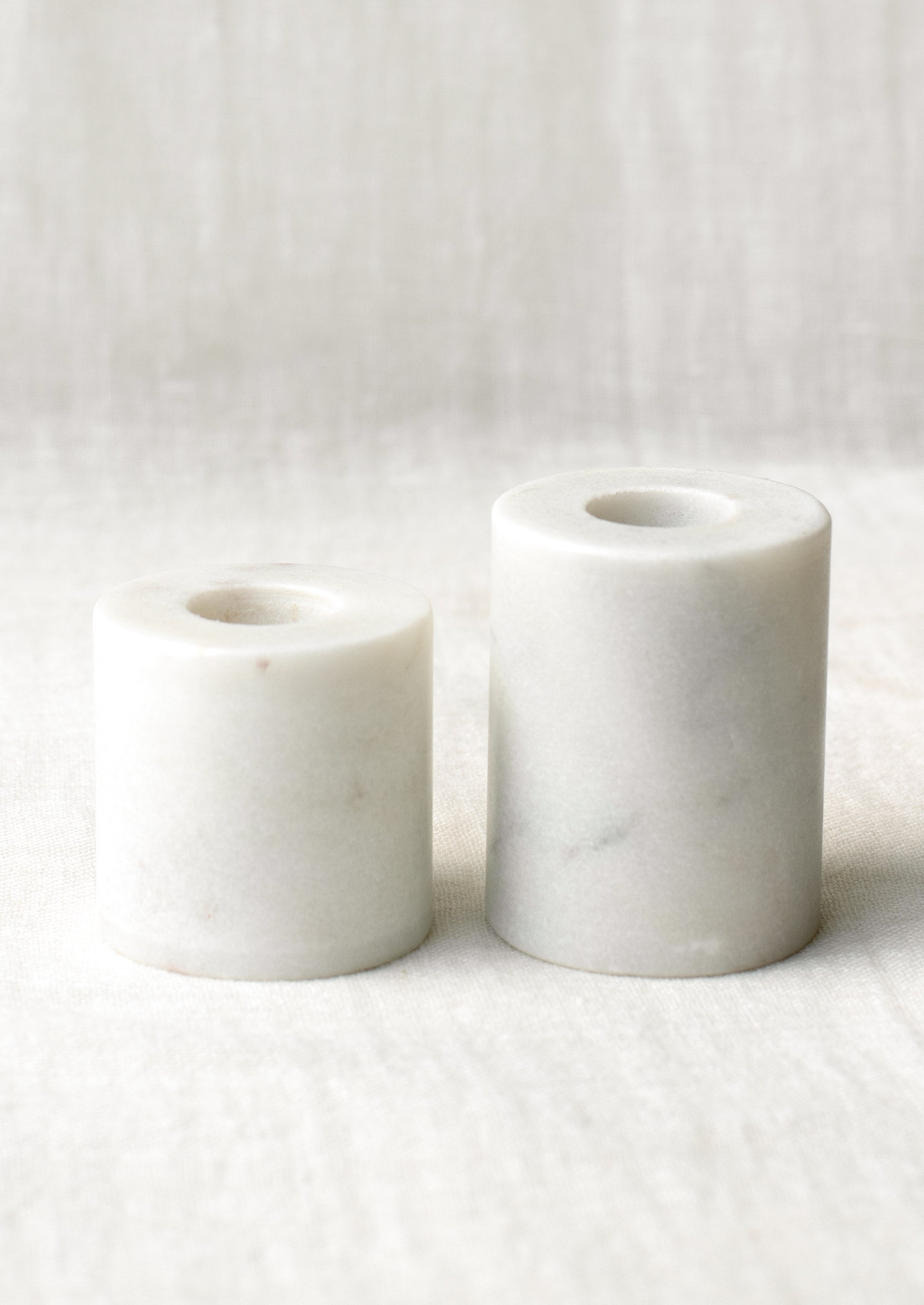 Cylindrical candleholders in two different height options, in white marble.