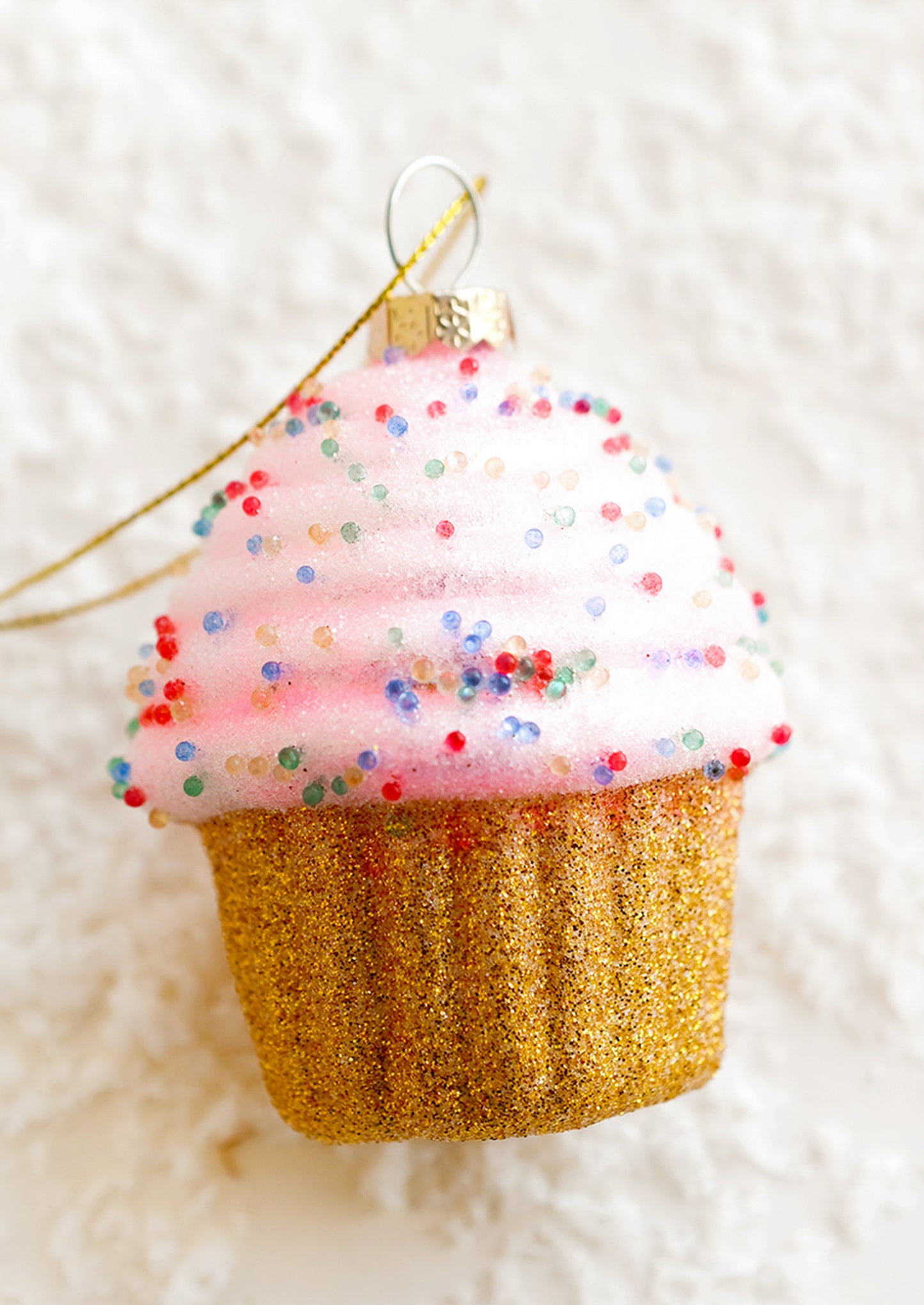 A holiday ornament of a pink cupcake.