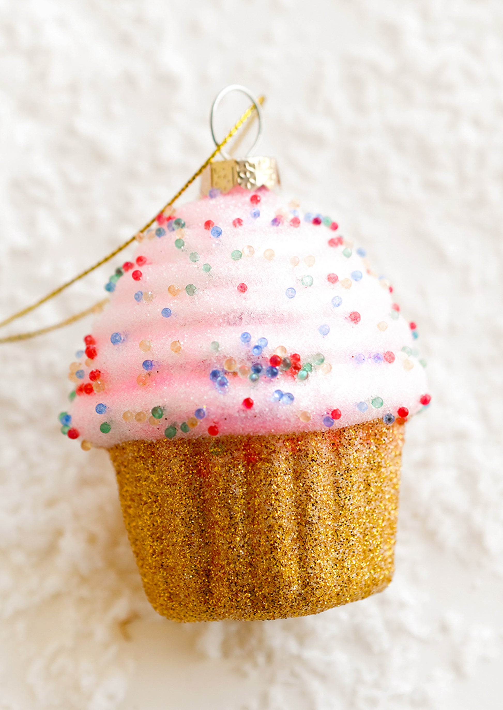 A holiday ornament of a pink cupcake.