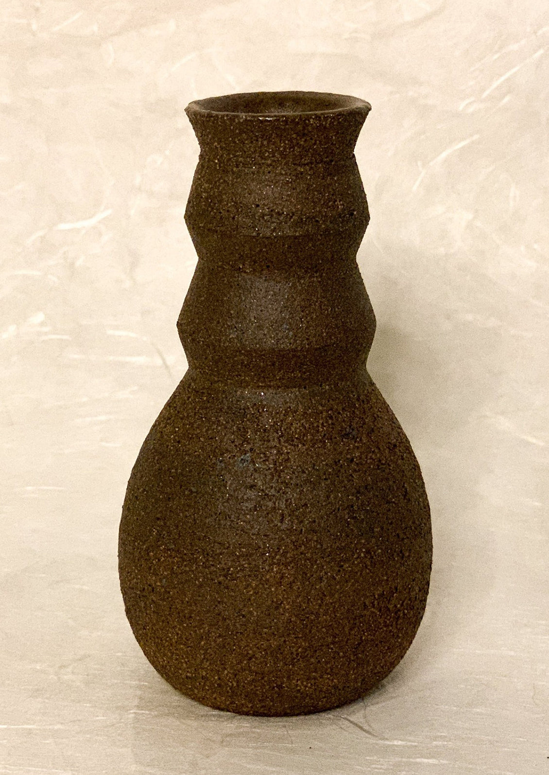 A sculptural, angular vase in dark brown ceramic.