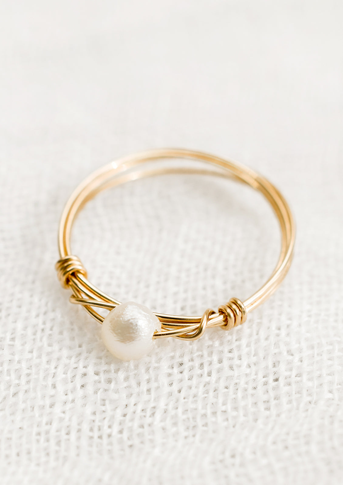 A gold wire ring with single pearl bead.