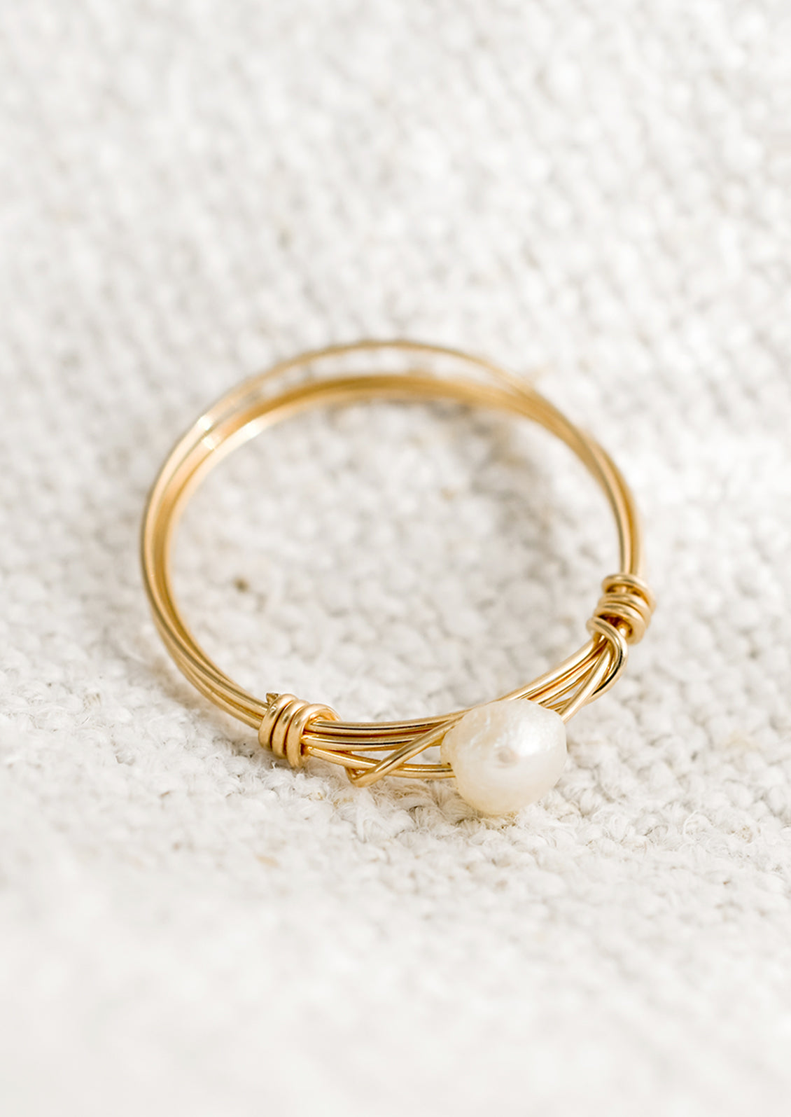 A gold wire ring with single pearl bead.