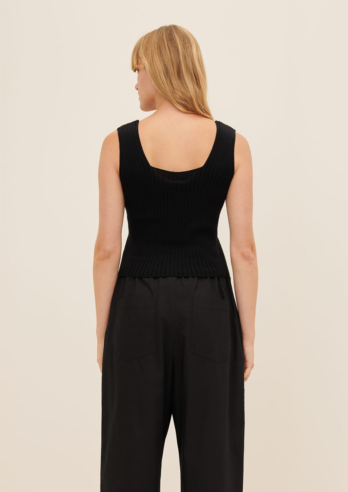 A person wearing a sleeveless, square neck rib knit top in black.