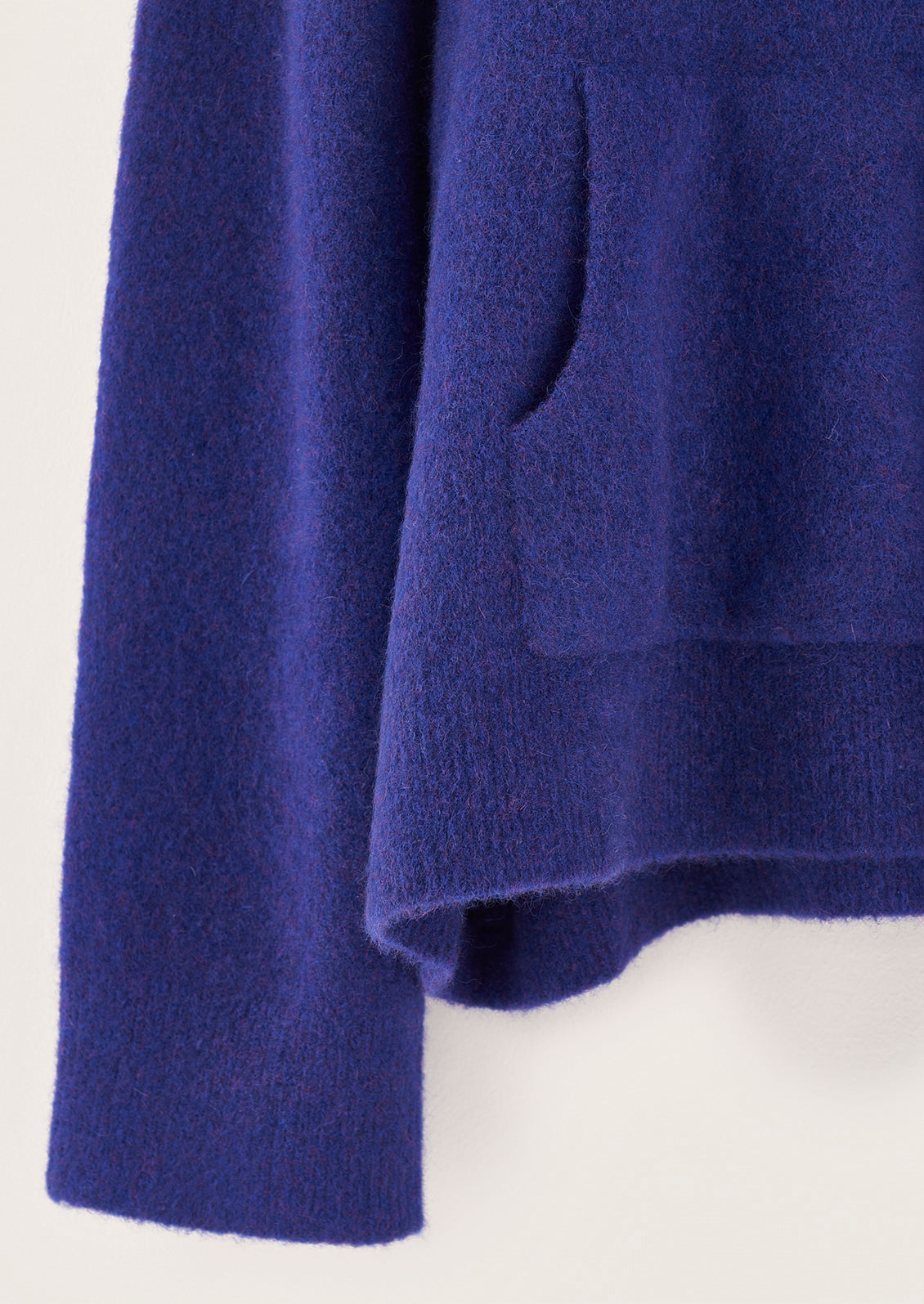 A woman wearing a hooded sweater with kangaroo pocket in vibrant cobalt blue color.