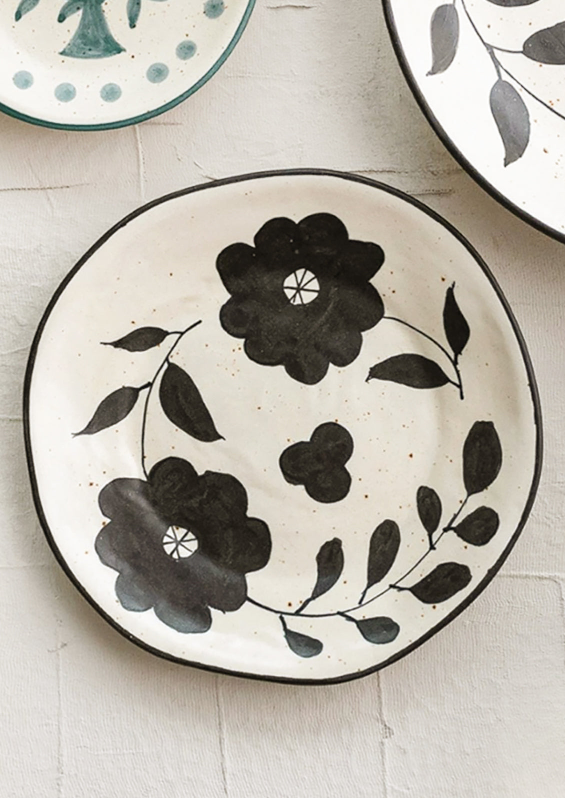 A round black and white ceramic platter with large scale black floral pattern.