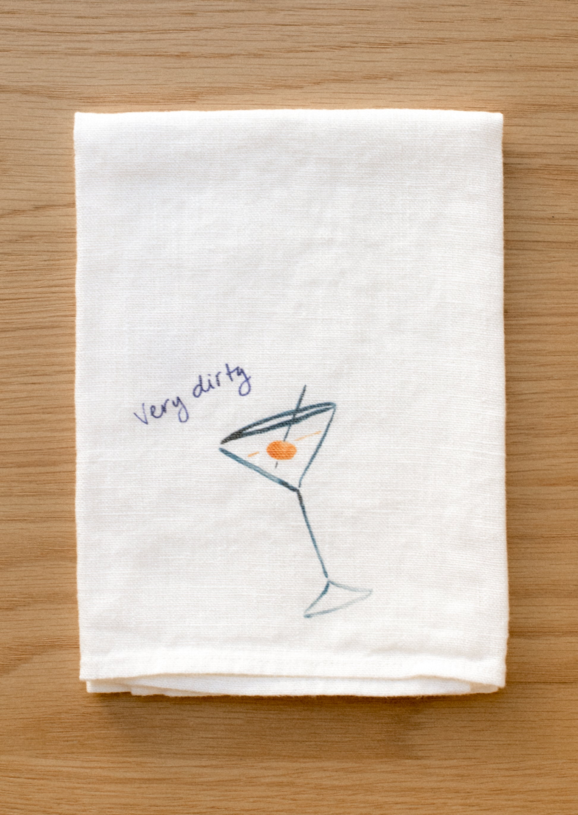 A white linen napkin with graphic detail of dirty martini.