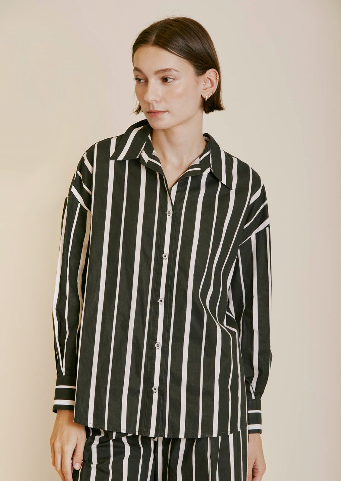 A poplin button front shirt in black with white stripes in varying widths.