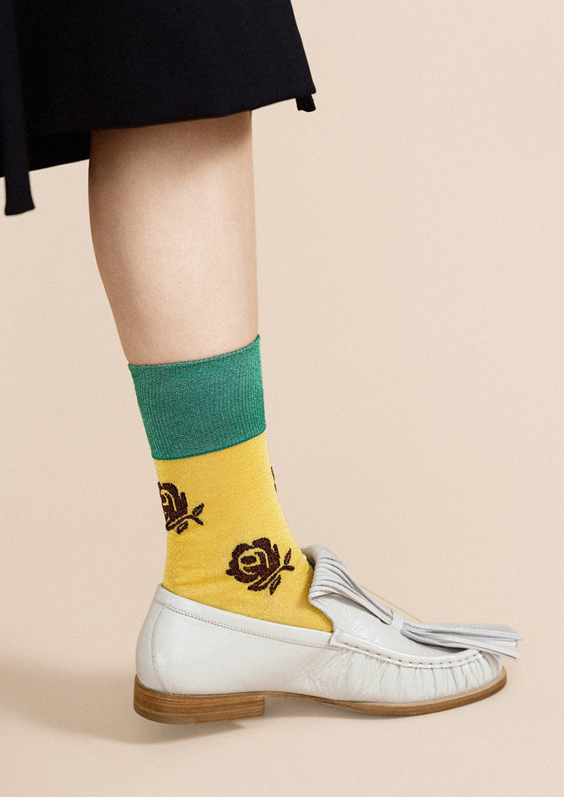 A woman wearing a pair of yellow and green socks with brown metallic rose pattern.