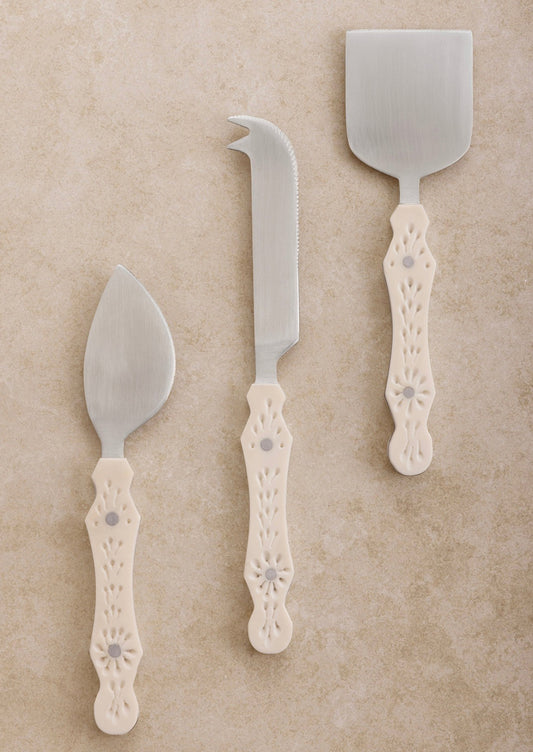 Three different cheese knife styles in silver with eyelet detailed cream resin handles.