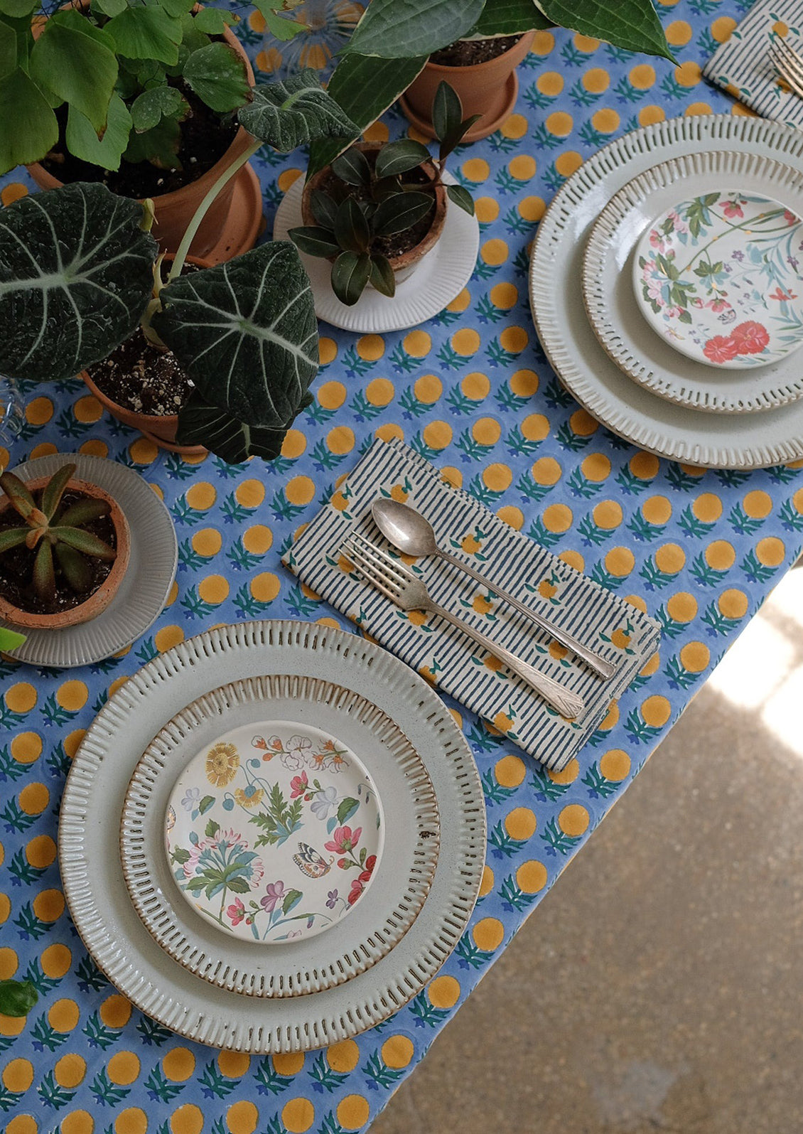 A blue tablecloth with yellow, blue and green block printed floral pattern.