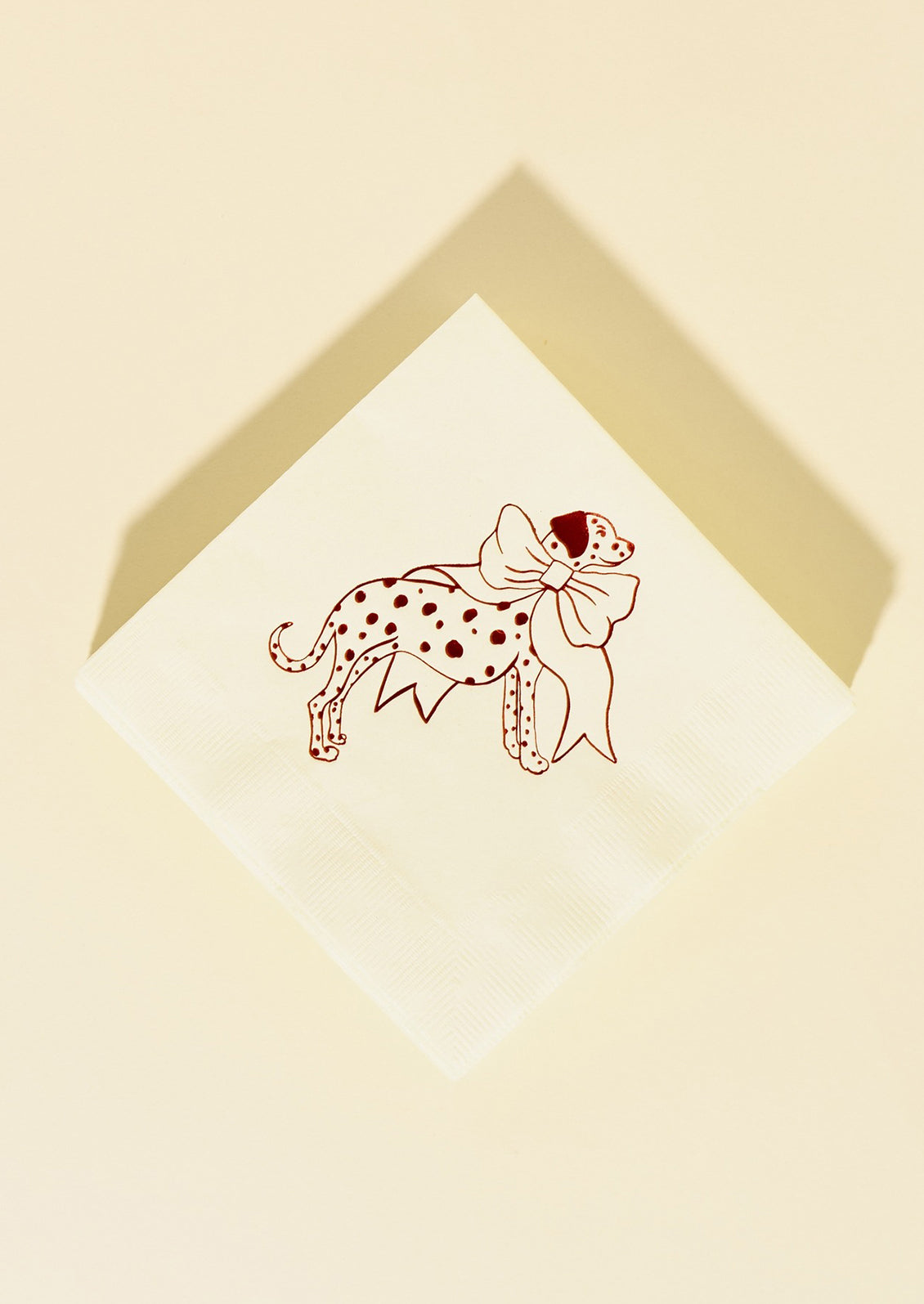 A set of white paper napkins with red foil image of dalmatian wearing a large bow.