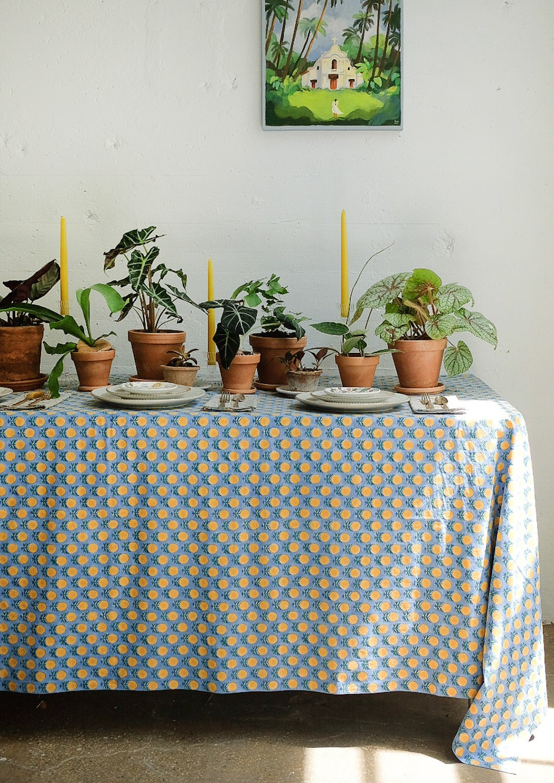 A blue tablecloth with yellow, blue and green block printed floral pattern.