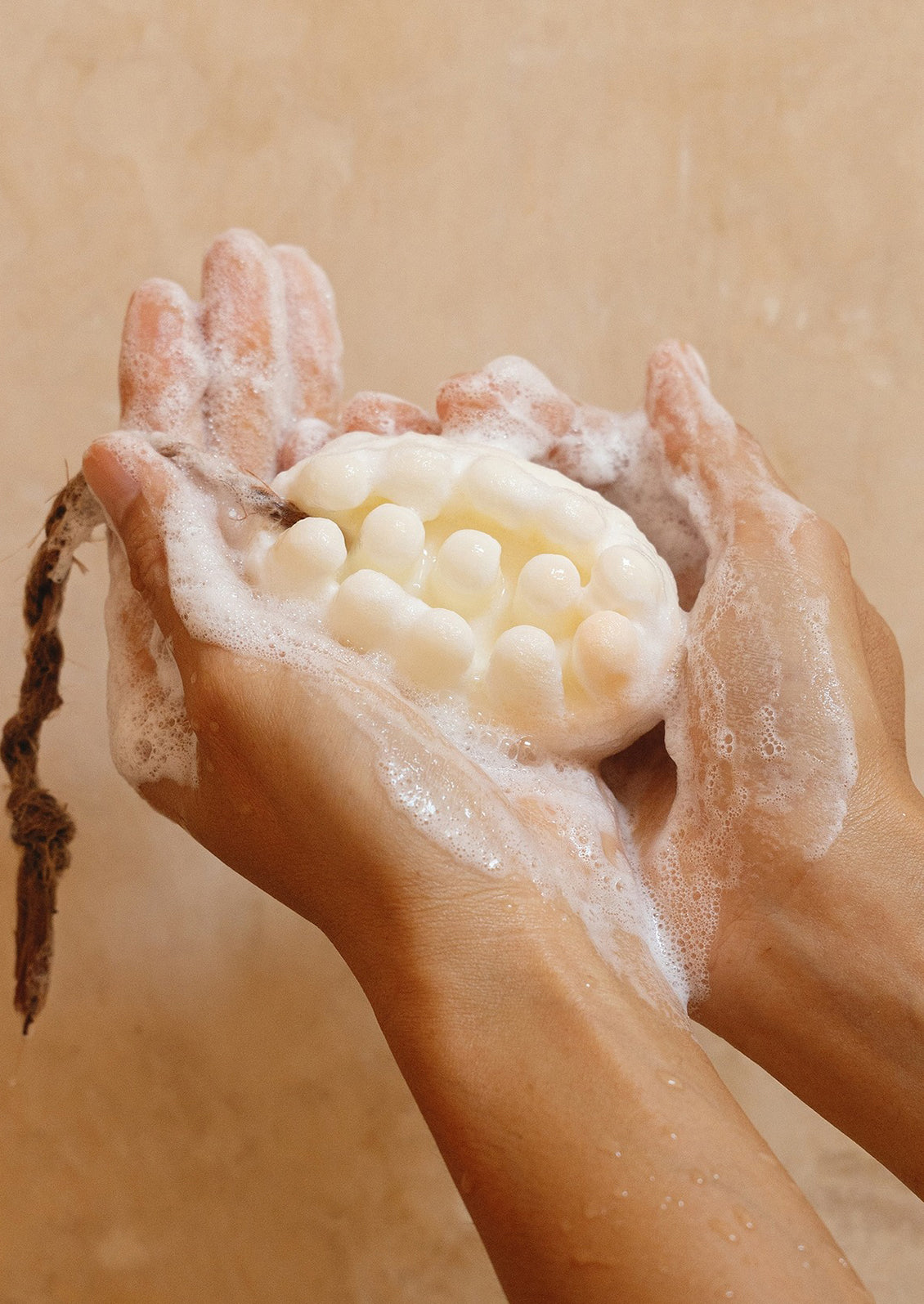 A person holding a massager-style bar of soap in their hands.