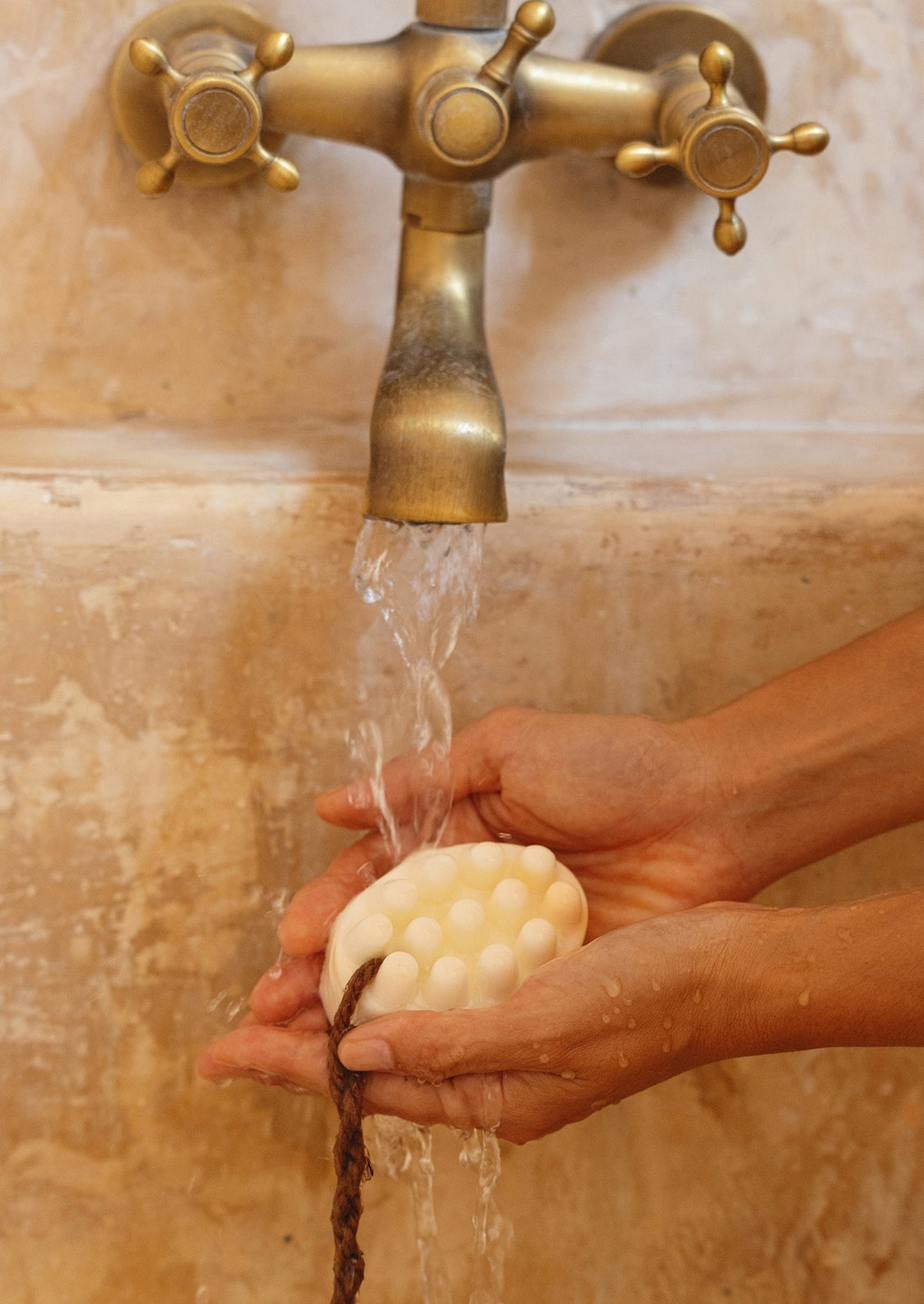 A person holding a massager-style bar of soap in their hands.