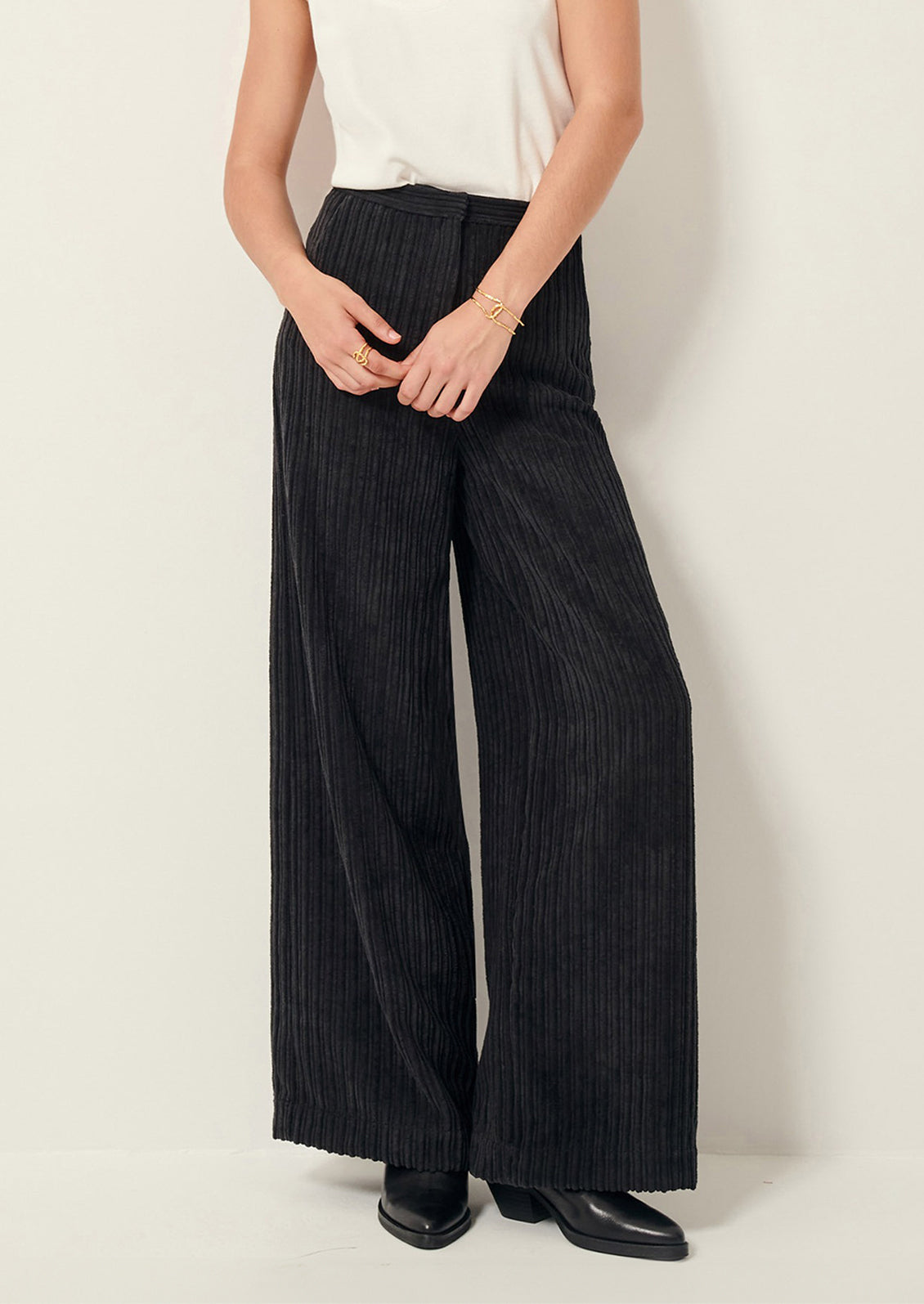 A woman wearing a pair of dark grey corduroy pants in wide leg.