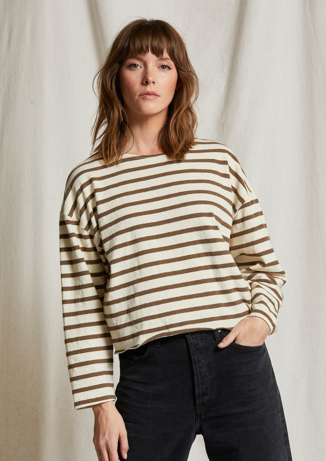 A woman wearing a long sleeve t-shirt in natural cotton with brown stripes.