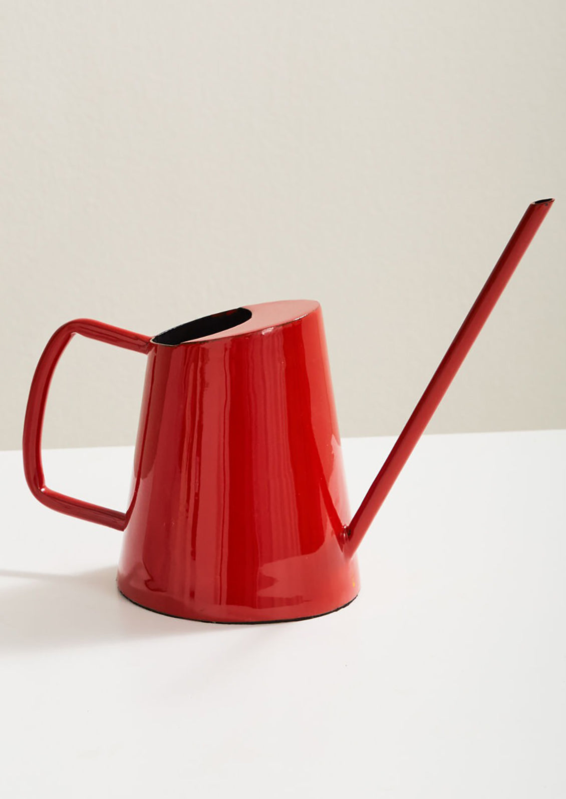 An enameled watering can with modern shape and cherry red hue.